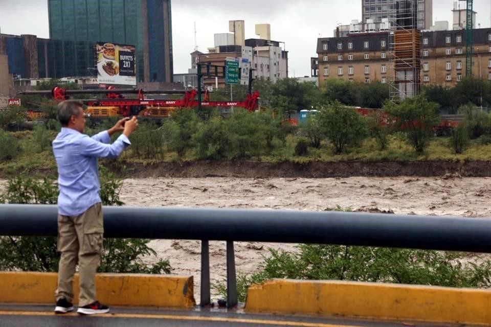 Curiosos se detenían en los márgenes del Río Santa Catarina para captar el cause.