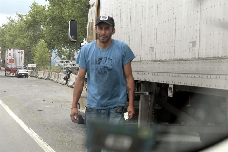 Hombres y mujeres ondena con vigor franelas, ponen en el suelo garrafas y bidones, y esperan llamar la atención a orilla de carretera de posibles compradores del producto robado de ductos de Pemex.