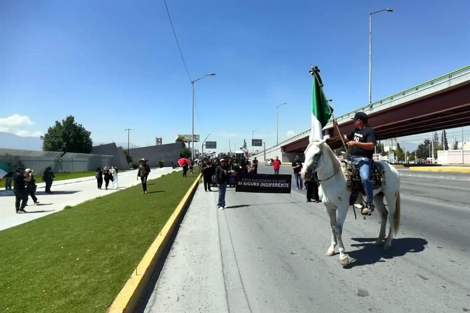 La manifestación de los empleados inició con un hombre a caballo con la bandera nacional.