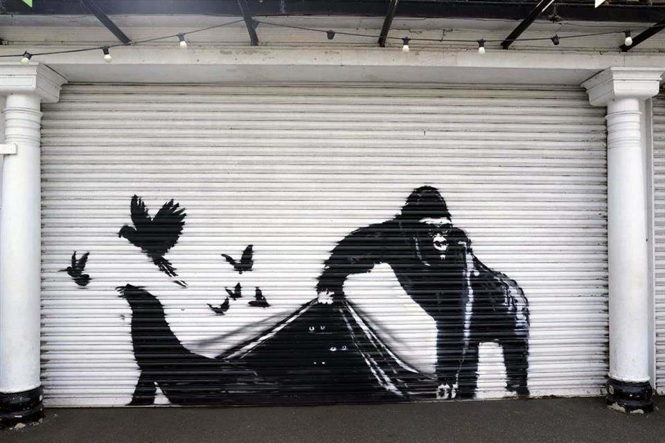 La obra de Banksy sobre la reja metálica de entrada al parque muestra a un gorila liberando a unos pájaros y una foca, mientras que varios pares de ojos brillan en la oscuridad.