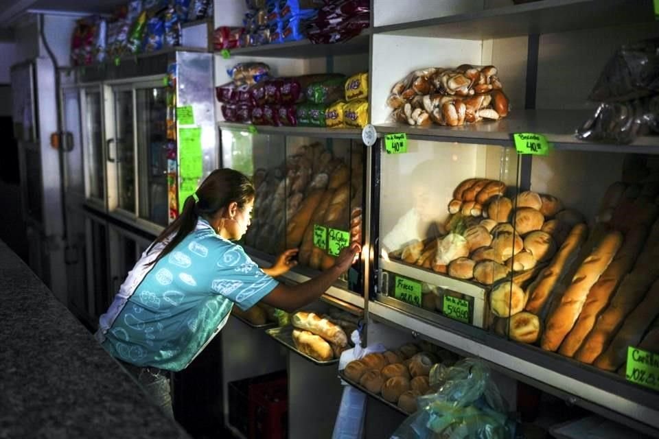 Una trabajadora de una panadería ajusta la tienda iluminada con la luz del sol de la mañana, durante un apagón, en Caracas.