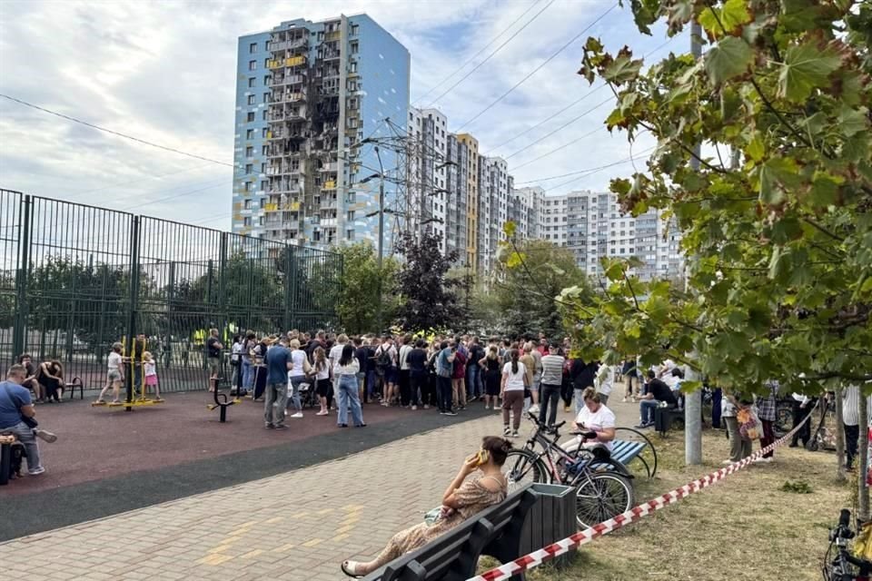 La gente se reúne afuera del edificio residencial de varios pisos dañado, luego de un presunto ataque con aviones no tripulados ucranianos en Ramenskoye, en las afueras de Moscú.