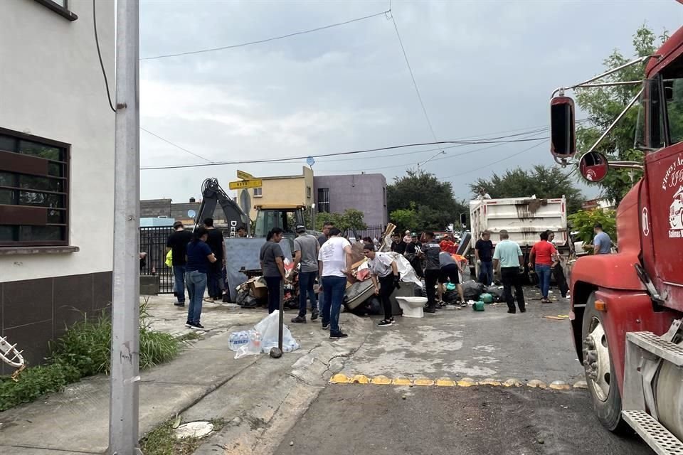 Vecinos de la Colonia Los Pilares y cuadrillas de Salinas Victoria limpian la zona afectada por las inundaciones.