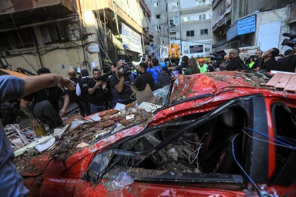 Transeúntes observan la destrucción en una calle debajo de un edificio residencial cuyos dos pisos superiores fueron alcanzados por un ataque israelí en el área de Ghobeiri,el sur de Beirut.