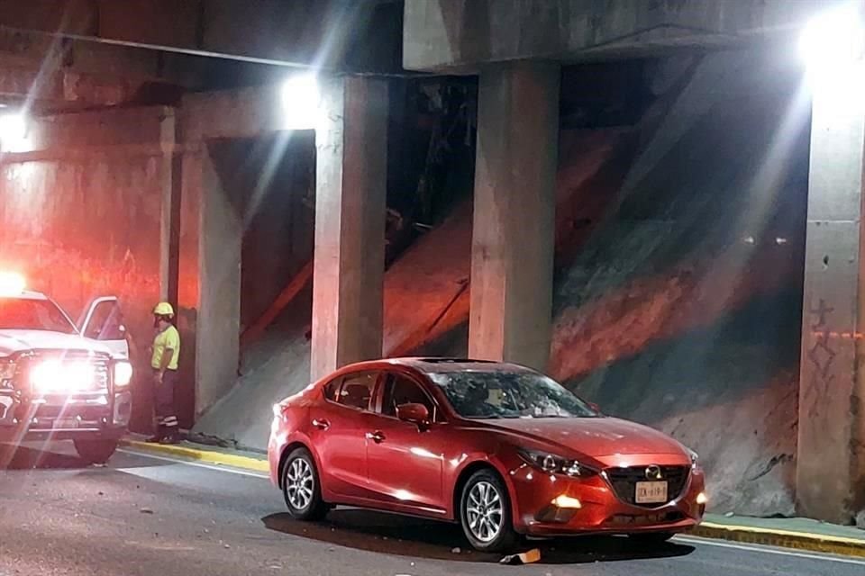 Un auto Mazda queda con daños en parabrisas y cajuela al caerle pedazos de concreto por una pipa que golpeó el techo de un paso a desnivel.