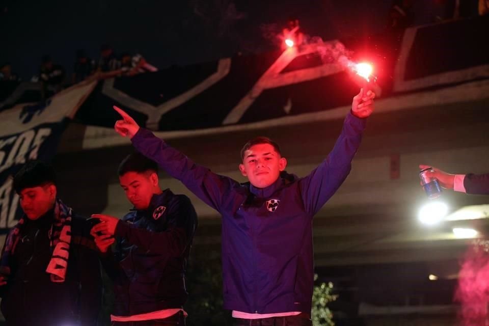 Un aficionado de Rayados ilumina con una bengala en las afueras del estadio albiazul.