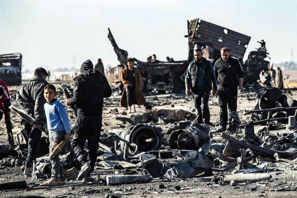 La gente recoge metal y municiones sin explotar del lugar del ataque aéreo israelí de la noche anterior contra cargamentos de armas que pertenecían a las fuerzas gubernamentales de Siria en Qamishli.