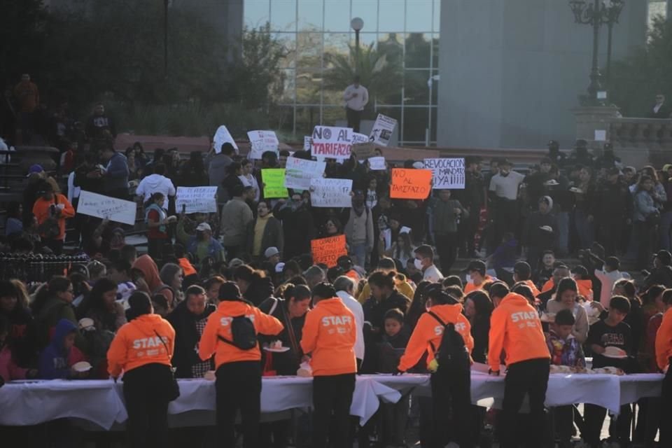 Mientas decenas de usuarios protestan contra el alza de tarifas, ciento de ciudadanos esperan por una rebana de la mega rosca de Reyes.