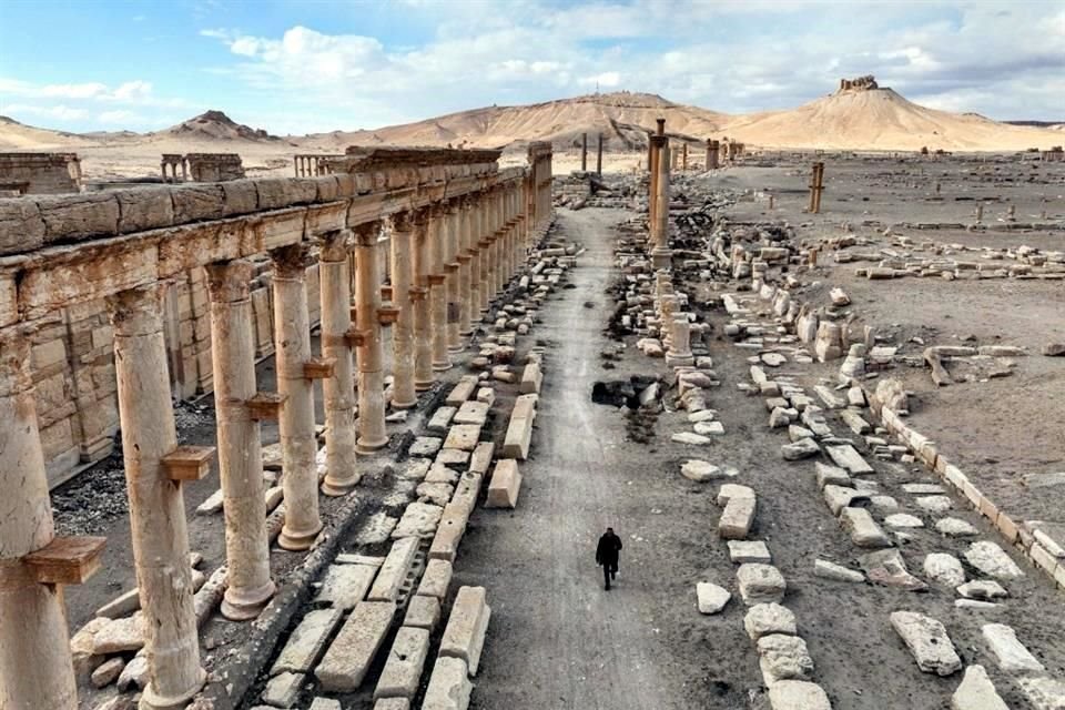 Una persona camina frente al gran conjunto de columnas.