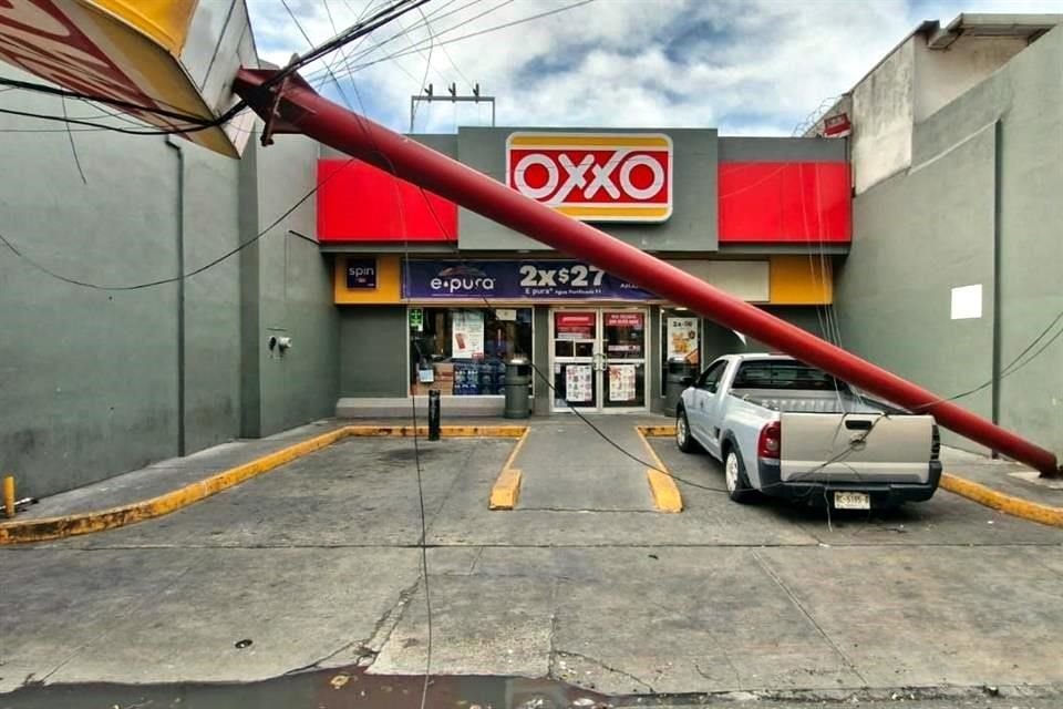 Un anuncio de una tienda Oxxo quedó sostenido por unos cables.