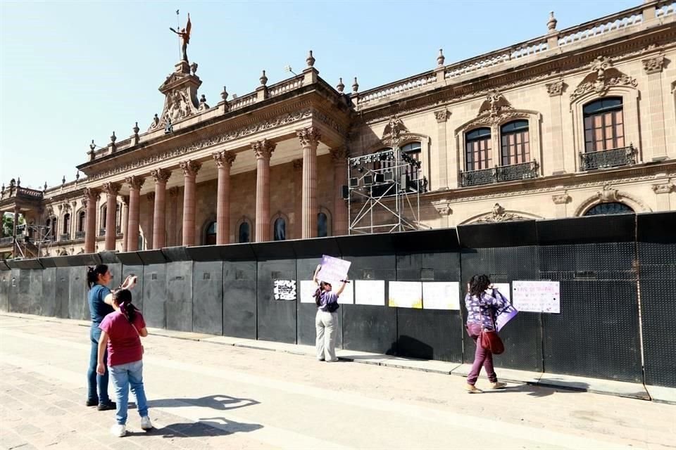 Algunas mujeres comenzaron a pegar pancartas en las vallas puestas alrededor del Palacio de Gobierno.