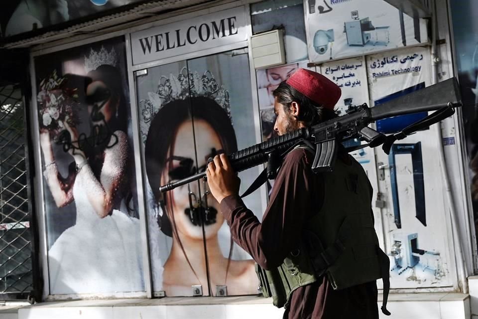 Un combatiente talibán camina frente a fotografías vandalizadas de mujeres en Kabul.