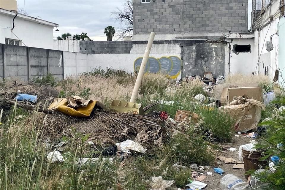 En la calle Torreón, en medio de dos casas habitadas por familias, el baldío abandonado acumula hierba crecida y basura de todo tipo.
