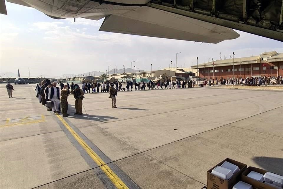 Afganos en Kabul hacen fila para ser evacuados en un avión militar.