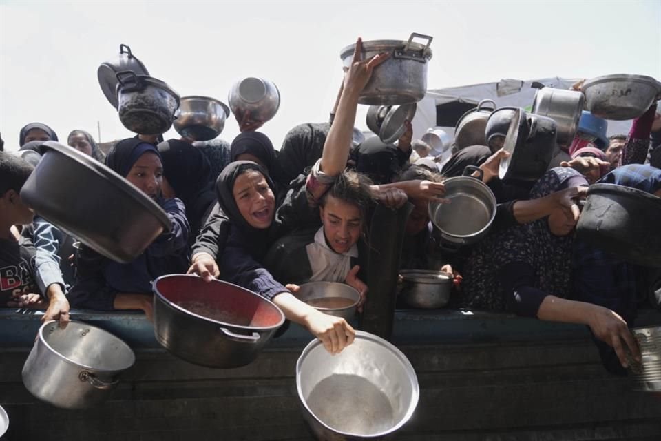 Palestinos intentan alcanzar ración de comida donada en un comedor comunitario en Jan Yunis, en la Franja de Gaza.