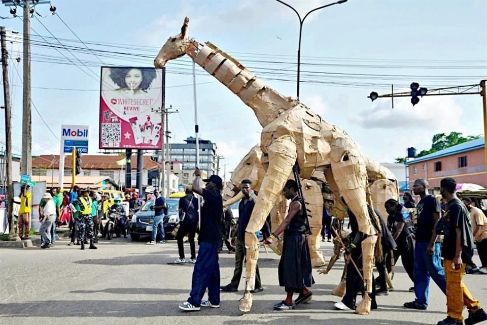 Una gran marioneta de una jirafa se mueve con ayuda de titiriteros para contar la historia 'The herds'.