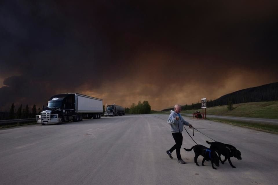 Un hombre pasea a sus perros bajo el cielo ennegrecido por los incendios, en British Columbia, el 30 de mayo.