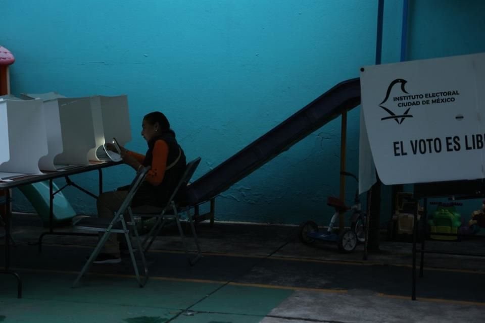 Al caer la tarde, una de las últimas votantes de una casilla se auxilió de la linterna de su celular para votar.