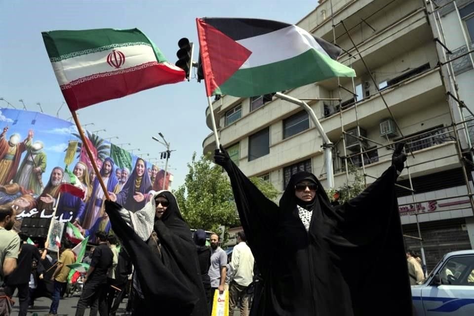 Manifestantes iraníes ondean banderas de Irán y Palestina en una concentración contra Israel en Teherán, Irán, el 13 de junio de 2025.