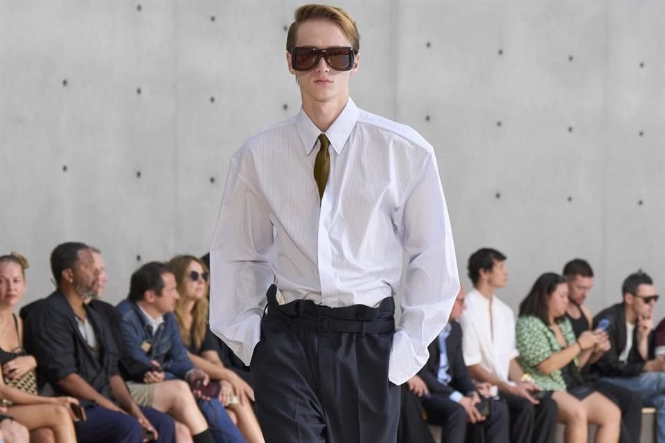 Pantalones largos en tono azul oscuro combinado con camisa blanca holgada y lentes de sol.