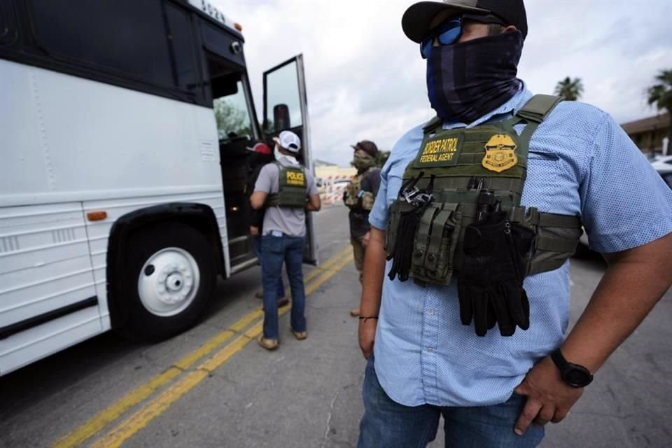 Un agente de la Patrulla Fronteriza observa cómo una familia de Colombia es detenida y escoltada hasta un autobús por agentes federales, en San Antonio