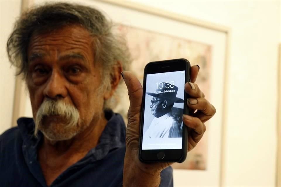 Francisco Toledo está mostrando su celular con la fotonde su abuelo en quien parte de su obra está inspirada en él por que era zapatero y puso toros en sus cuadros por que decía que con esa piel hacía