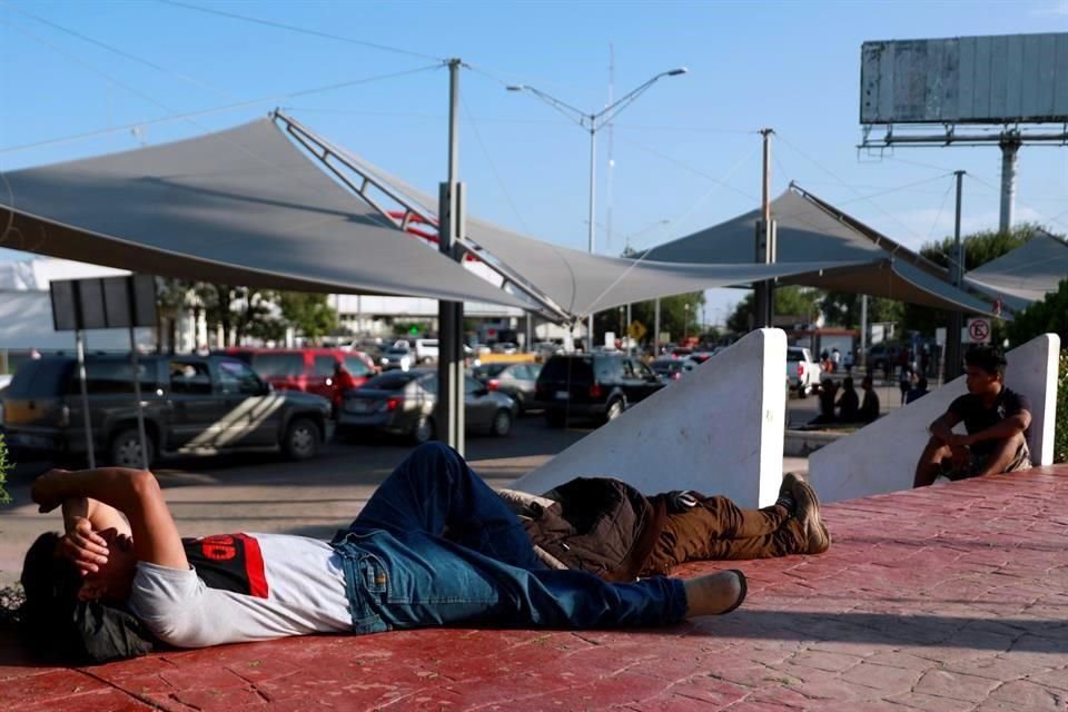 Migrantes de Centroamérica descansan cerca de un campamento en Matamoros, México, mientras esperan que se atiendan sus solicitudes de asilo en EU.