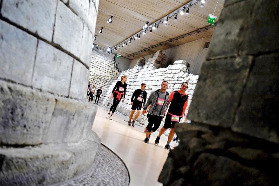 En esta imagen se aprecia a personas caminando y corriendo dentro del Louvre de París.