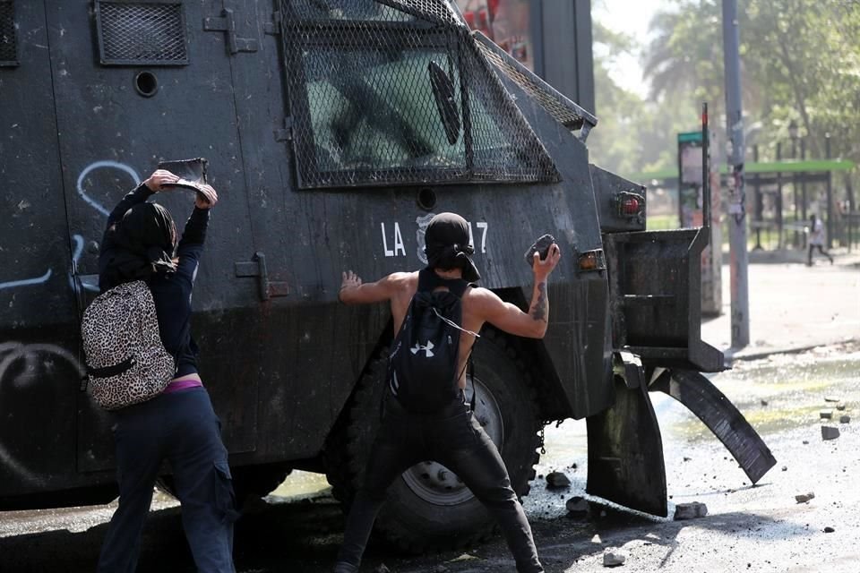 Manifestantes avientan piedras a vehículos de la Policía.