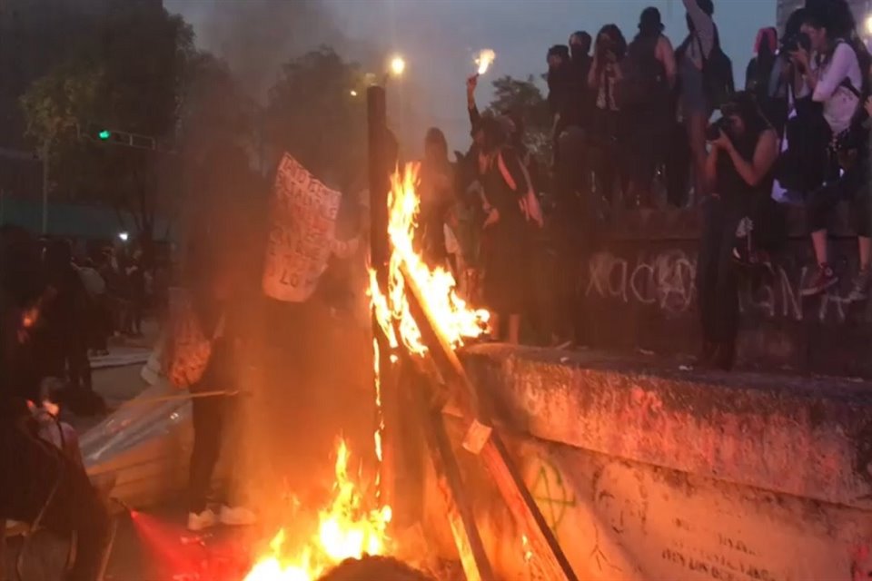 Mujeres con el rostro cubierto quemaron pedazos de madera en el Monumento a Cuauhtémoc donde también realizan pintas y destrozos.