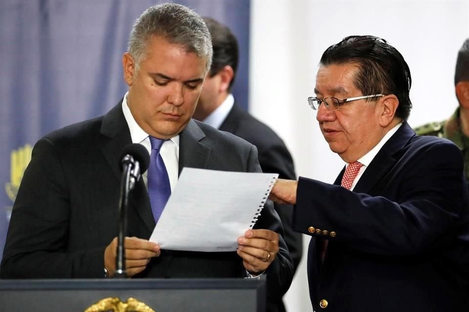 Iván Duque lee una hoja de papel junto al Ministro de Salud colombiano, Fernando Ruíz, antes de dirigirse a los medios en una rueda de prensa este jueves, en Bogotá, Colombia.