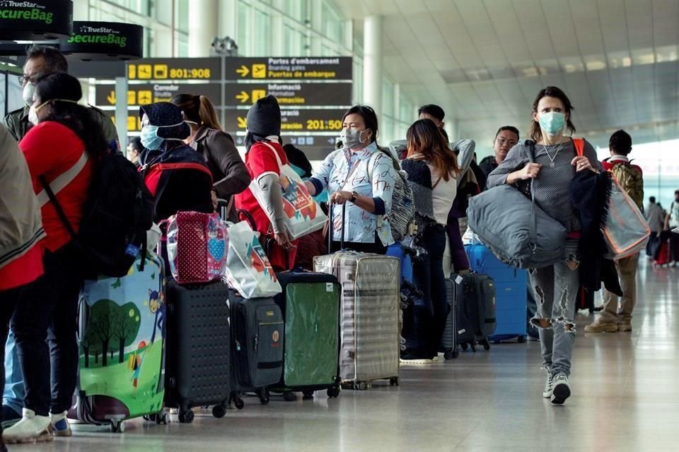 Varios viajeros transitan por el aeropuerto de Barcelona este sábado, muchos de ellos con mascarillas.