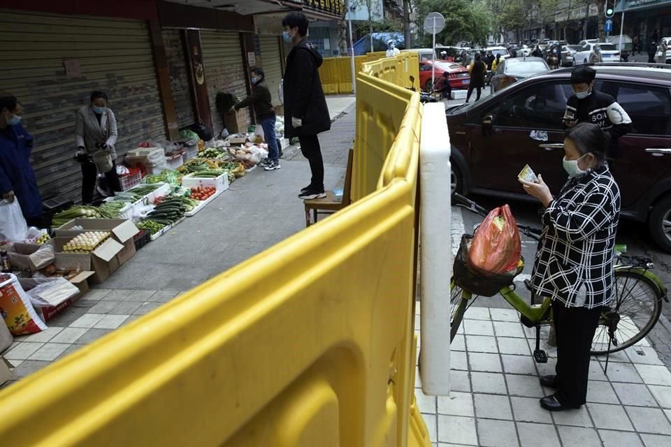 La ciudad de Wuhan, donde primero se detectó el virus en diciembre pasado, permanece bajo encierro. Una valla separa a los ciudadanos de los vendedores de alimentos.