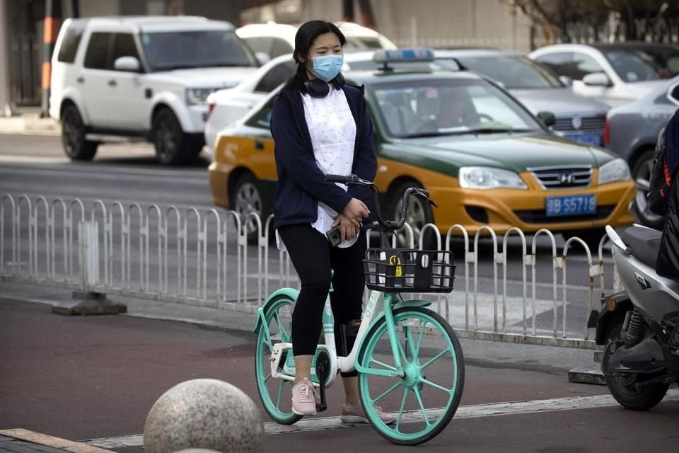 Una ciclista en Beijing guarda tres minutos de silencio por las víctimas de coronavirus.