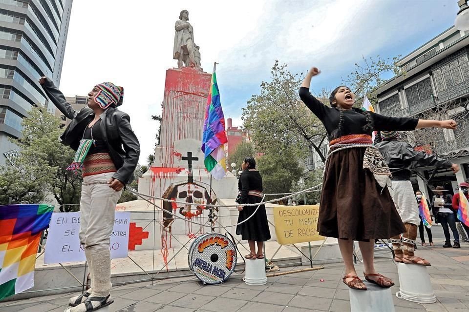 Activistas y artistas protestan en La Paz, Bolivia, frente  a la estatua de Cristóbal Colón, con pintura roja y otros símbolos