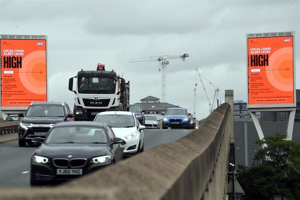 Decenas de automovilistas circulan cerca de un aviso que anuncia que el nivel de alerta de Covid es alto en Canary Wharf, en Londres.