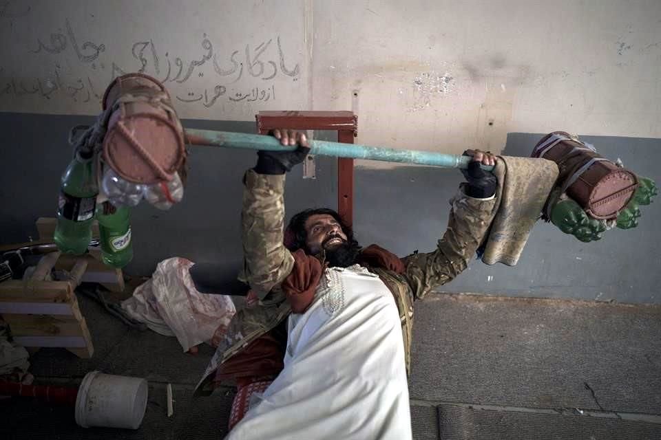 Un combatiente talibán prueba las pesas que los reos hicieron en la prisión.