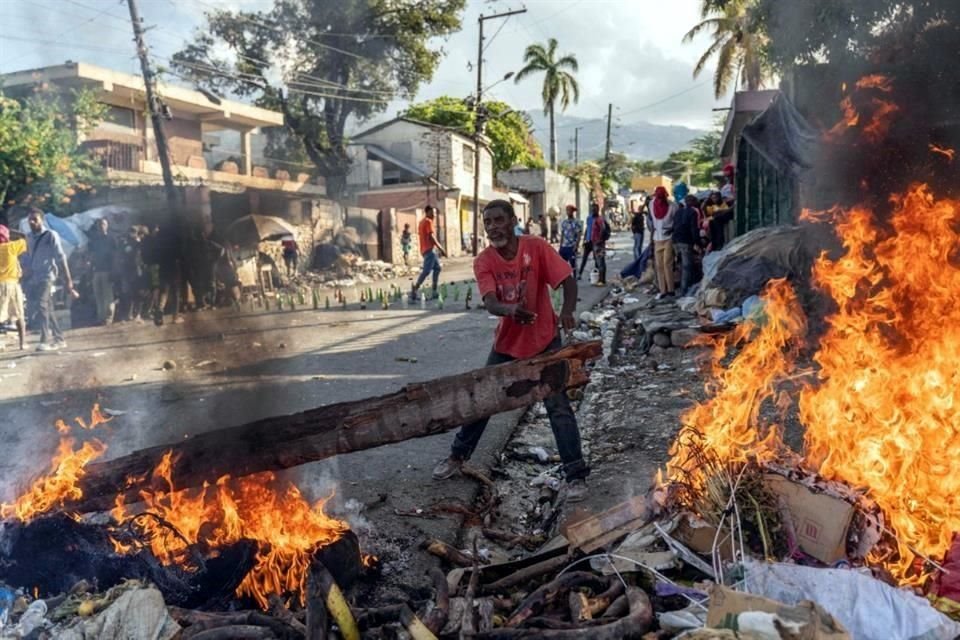 Un hombre añade madera a un incendio durante protestas contra el Gobierno, en Puerto Príncipe, Haití.