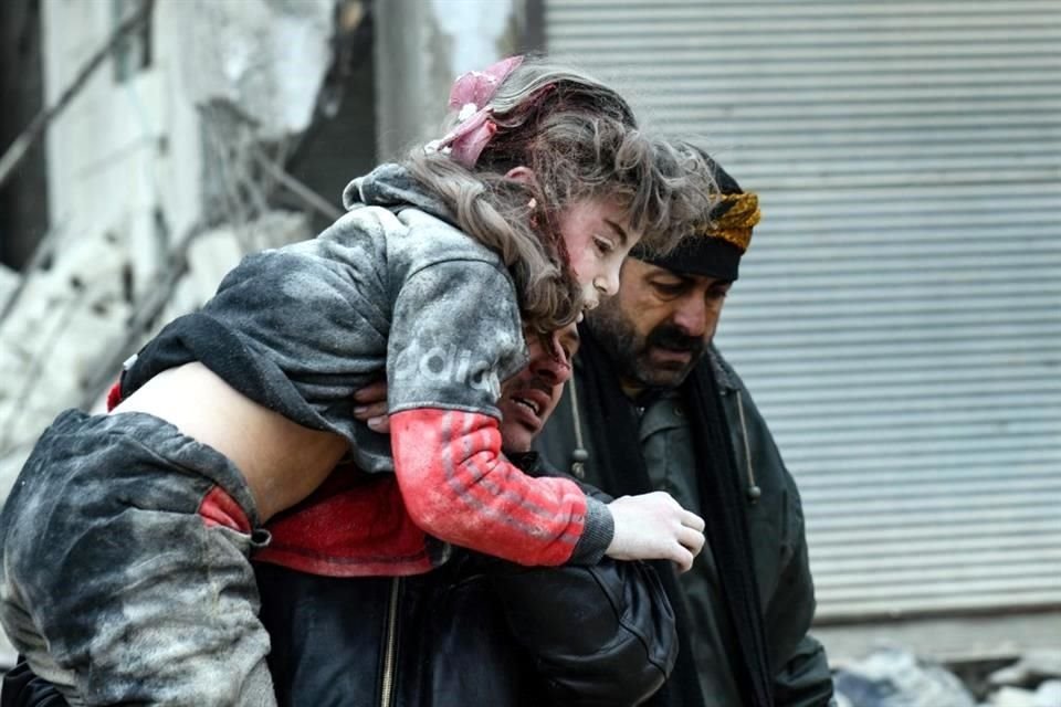 Residentes cargan a un niño rescatado tras el sismo de 7.8 en Siria.