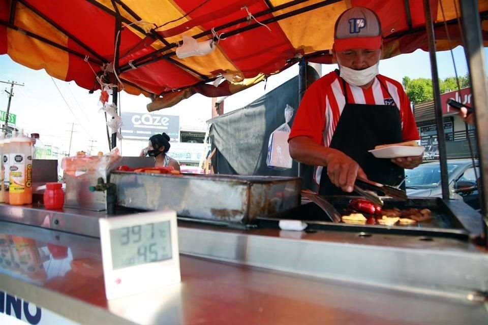 Don Chuy, un vendedor de hot dogs, soporta los casi 40 grados junto al comal donde prepara los alimentos.