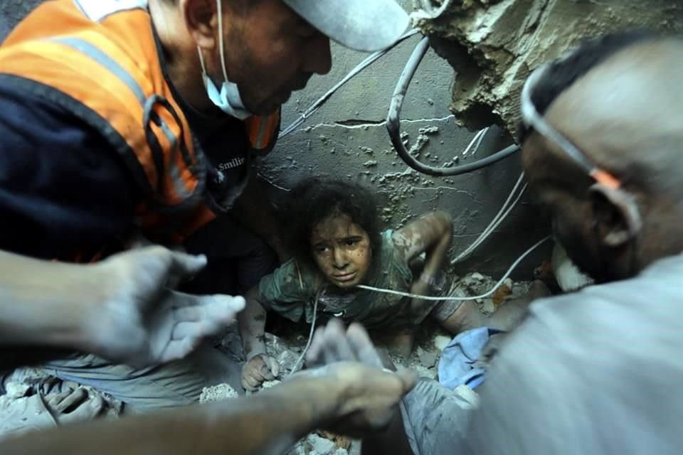 Los palestinos intentan sacar a una niña de los escombros de un edificio destruido por los ataques aéreos israelíes en el campo de refugiados de Jabaliya.