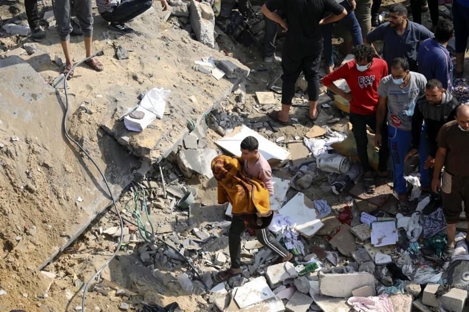 Un hombre palestino carga a un niño muerto que fue encontrado bajo los escombros de un edificio destruido.