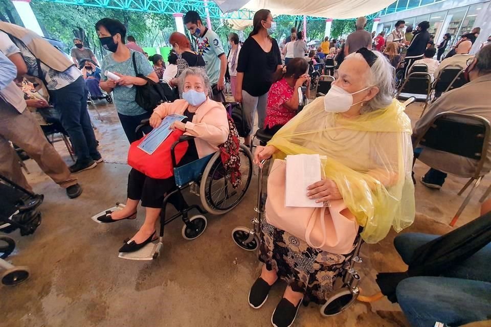 Doña Fidela (der.), de 81 años, tuvo que ir bajo la lluvia al Parque España para recoger un giro de pago del apoyo federal.