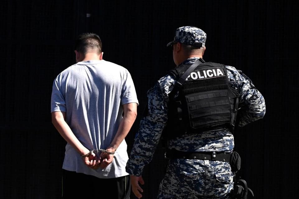 Un hombre arrestado por presuntos lazos con pandillas es escoltado por un oficial en San Salvador, el 22 de junio del 2022.