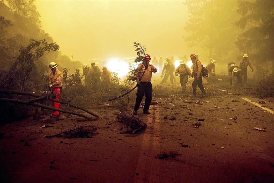 Bomberos batallan por liberar una carretera en el condado Plumas de California, la cual resultó afectada por el incendio Dixie.