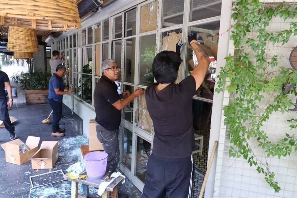 Trabajadores de una cafetería que fue vandalizada durante protesta contra la gentrificación realizan el retiro de cristales rotos, despintan grafitis y reparan mobiliario.