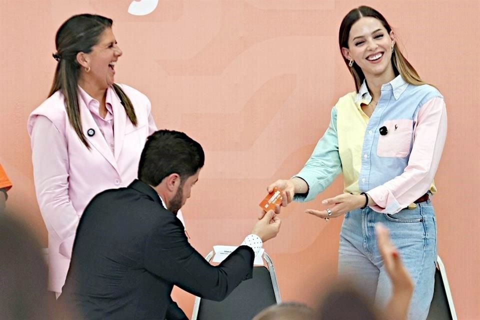 Announcing an increase in handouts for women, supposedly at his wife's request, the Governor symbolically handed her a support card in front of Martha Herrera (left).