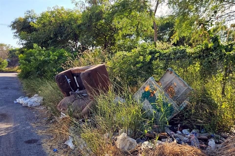 En el espacio donde debería haber una banqueta, en la calle Córcega, presenta maleza cecida y por su descuido ha sido convertida en un depósito irregular de basura.